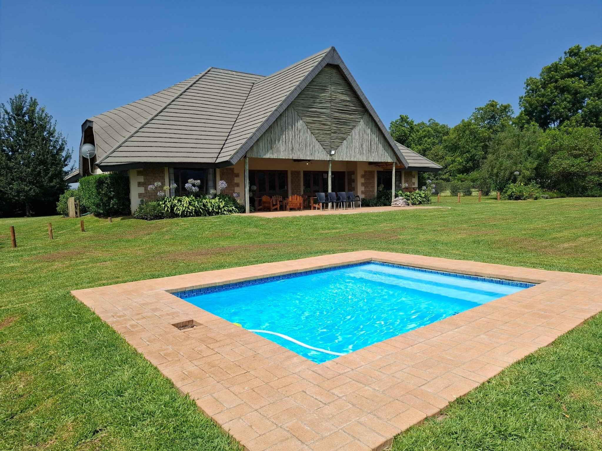 Plain Champagne Guest Farm Exterior With Pool Exterior view of the Plain Champagne Guest Farm homestead with thatched roof and sparkling blue pool in the Drakensberg