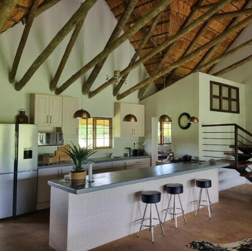 Open-Plan Self-Catering Farm Kitchen at Plain Champagne Spacious open-plan kitchen at Plain Champagne Guest Farm with central island, bar stools, and exposed timber roof
